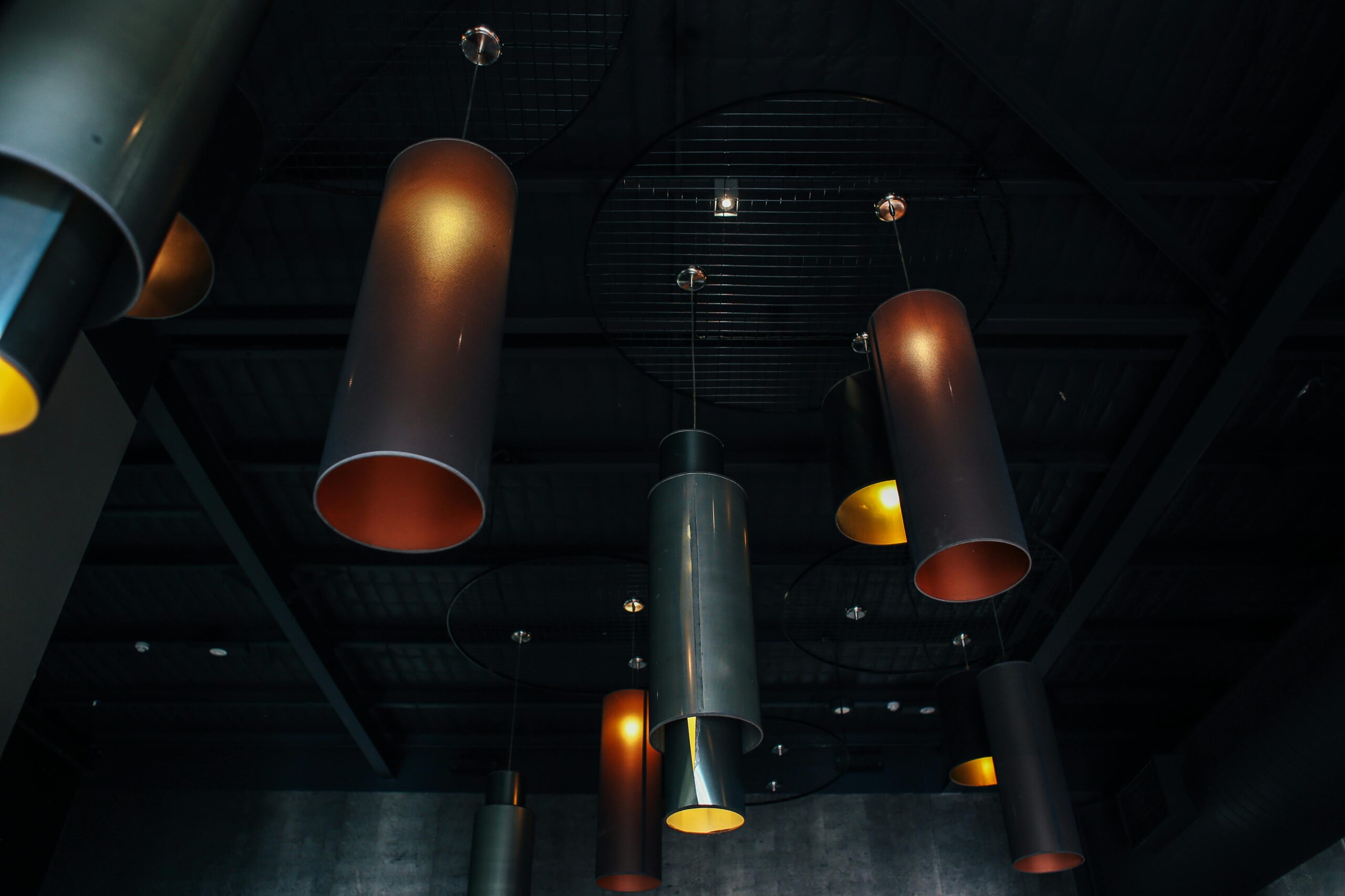 A low angle shot showcasing industrial style pendant lights against a dark ceiling, creating a moody atmosphere.